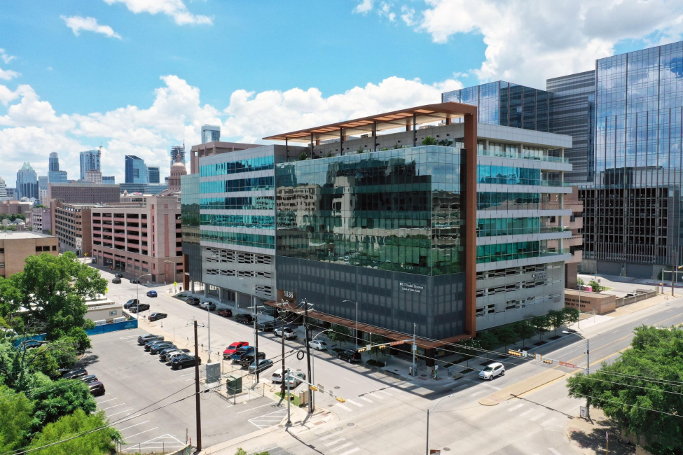 UTHealth Houston School of Public Health in Austin on the corner of San Jacinto Blvd, background shows an overview of the Austin Skyline